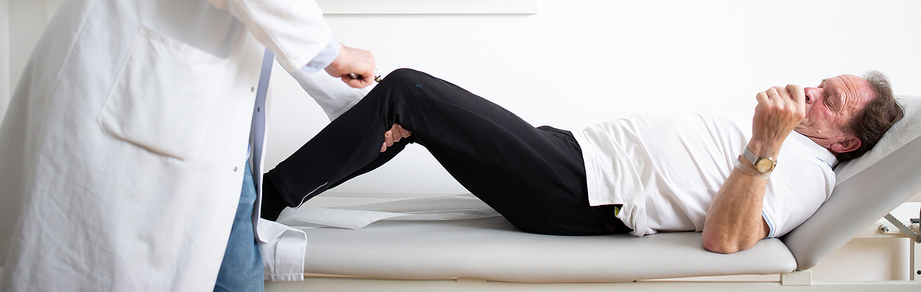 Ein Arzt untersucht einen Patienten auf einer Liege.