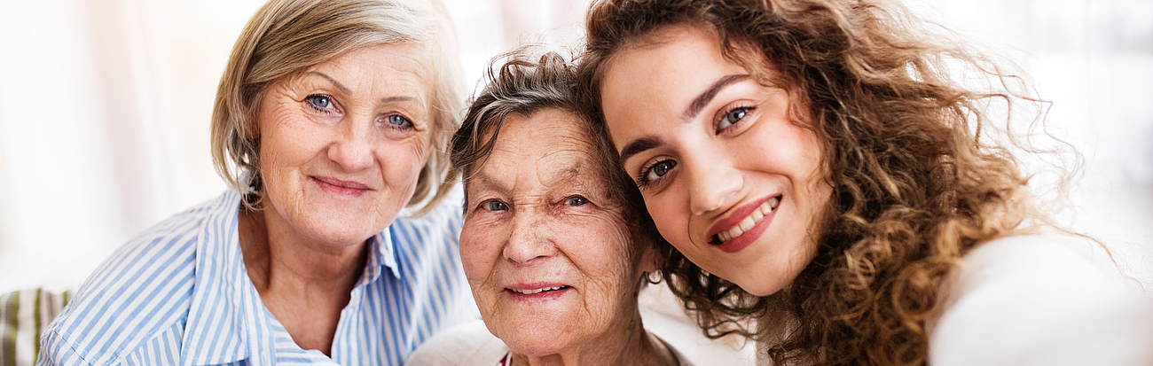 Drei Frauen unterschiedlichen Alters lachen in die Kamera.